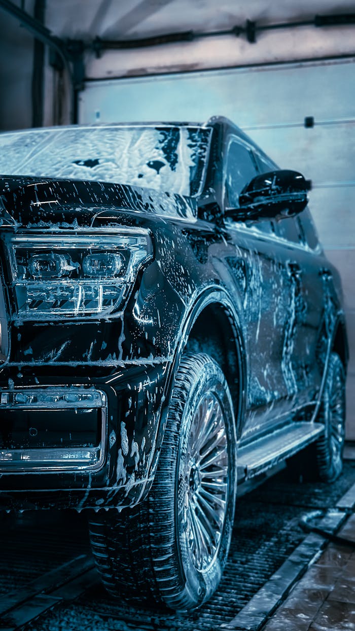 Close-up of a sleek SUV covered in soap during a car wash, highlighting cleanliness and care.